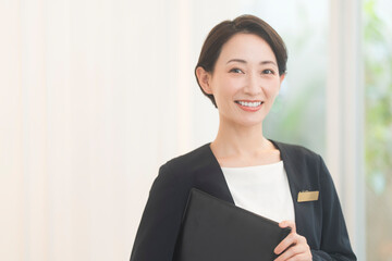 プランナー。ジャケットを着て黒いファイルを持つ笑顔の日本人女性。