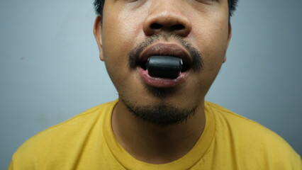 Close-up of a man using a jawline training tool placed in his mouth, associated with mewing and facial muscle enhancement exercises.
