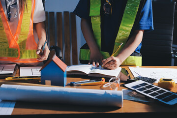 Closeup of team of industrial engineers meeting analyze machinery blueprints consult project on table in manufacturing factory. Working in manufacturing plant or production plant.