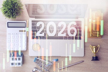 Stock market overlay on workspace with 2026 on laptop, surrounded by gold bar, bitcoin, house, calculator, and trophy symbolizing future investments.