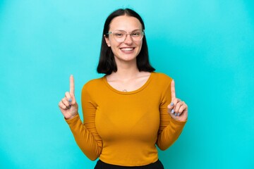 Fototapeta premium Young caucasian woman isolated on blue background pointing up a great idea