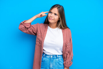 Young caucasian woman isolated on blue background making the gesture of madness putting finger on the head