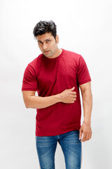 Young man wearing a red t-shirt, denim jeans, and sneakers posing casually in a studio against a plain white background. Ideal for themes of fashion, confidence, and modern lifestyle.