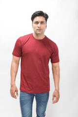 Fototapeta premium Young man wearing a red t-shirt, denim jeans, and sneakers posing casually in a studio against a plain white background. Ideal for themes of fashion, confidence, and modern lifestyle.