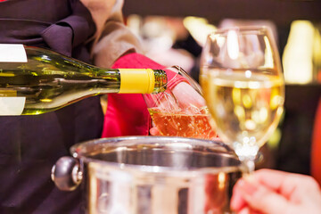 飲食店で、よく冷えた白ワインを注ぐ人