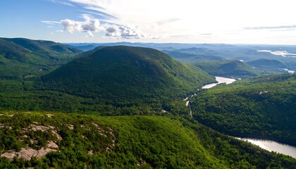 Fototapeta premium A sweeping vista of lush green mountains, valleys, and a winding river, showcasing the serene beauty of the landscape.