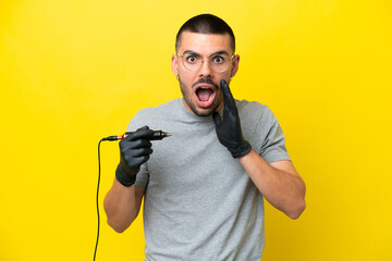 Tattoo artist caucasian man isolated on yellow background with surprise and shocked facial...