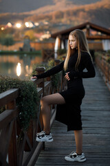 A woman leans on the railing of a wooden bridge