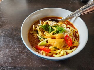 Bowl of Heavenly Curry Noodle with Fresh Vegetables and Toppings on a Table