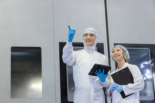 工場でタブレットPCを使う防護服を着た作業員