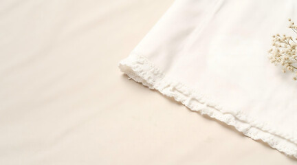Obraz premium White fabric with delicate lace trim and dried flowers on surface 