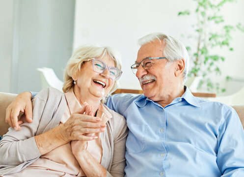 Portrait of a happy senior couple embracing talking and drinking coffee or tea at home