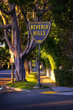 Beverly Hills, California, USA - November 3, 2023 : Beverly Hills sign at the corner of Sierra Drive and Sunset Boulevard, surrounded by lush greenery and illuminated by warm sunlight.