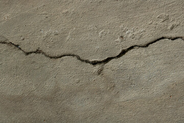 A crack running through a weathered concrete surface. An abstract background of decay and imperfection