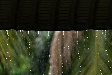 Heavy rain pouring down from a roof edge. Concept of shelter and peace during a storm