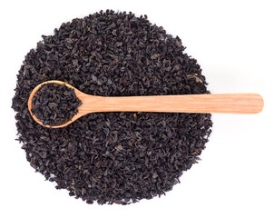Black tea leaves with wooden spoon top view isolated on white