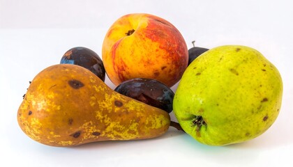 A peach, pears and plums arranged on a white background. One pear shows discoloration