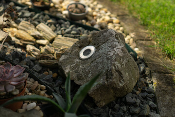 small outdoor led light embedded in a large gray rock in a garden setting, concept of home improvement, gardening, landscape design.