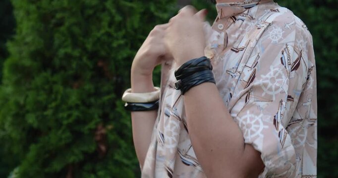 Woman with short black hair taking off her shirt on hot summer day and seeing that her armpits are wet, then she hurries to hide them. Concept of hyperhidrosis, sweat odor and excessive sweating.