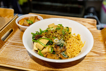 Assorted bowl of Taiwanese-style braised vegetables, tofu, mushrooms, and noodles garnished with green onions and pickled mustard greens