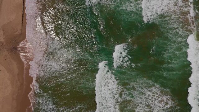 Aerial Top-Down Drone View of Ocean Waves Crashing onto Sandy Shore