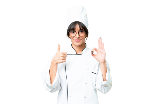 Young caucasian chef  woman over isolated chroma key background showing ok sign and thumb up gesture