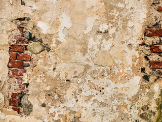Old weathered plastered wall revealing red brick wall where plastering has fallen off. Graphic background for design.