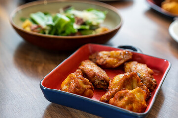 Roasted grilled chicken legs or baked chicken wings new orleans and barbecue or bbq in square plate with vegetables salad on wooden table for protein food or cuisine to lunch or dinner in restaurant