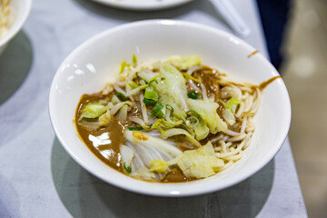 Close-up of sesame sauce noodles with shredded cabbage and bean sprouts in a white bowl, lightly tossed with a soy-based sesame dressing