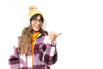 Young caucasian woman wearing winter muffs over isolated chroma key background pointing to the side to present a product