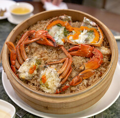 Steamed glutinous rice richly infused with crab juices and topped with orange roe, served in a bamboo basket with whole crab segments