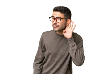 Young handsome caucasian man over isolated background listening to something by putting hand on the ear