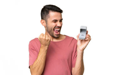 Young handsome caucasian man holding a engagement ring over isolated background celebrating a victory