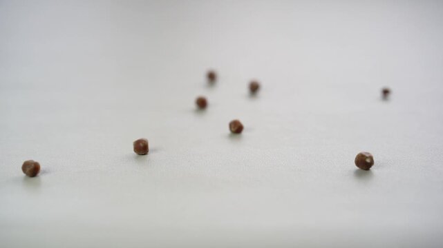 8 black gallbladder lumps or gallstones and kidney stones slow motion rolling or stone falling down from cholesterol or bad food on gray white table for medical background