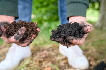 Close-up of two hands cradling a handful of highly fertile, dark soil enriched with organic matter, biochar, and thriving worms. Carbon farming, sustainable farming.