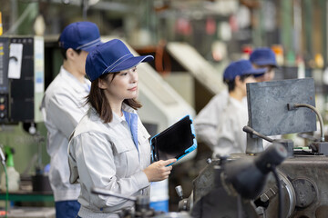 タブレットPCを持って機械を点検する作業員