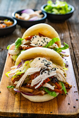 Bao Buns with pulled chicken and vegetables on wooden table