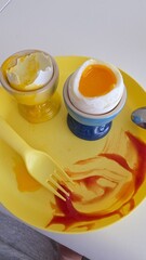 A soft-boiled egg with a runny yolk served in a blue egg cup. The cracked shell reveals the golden yolk, placed on a yellow plate, creating a bright and appetizing breakfast scene. bowl of soup