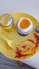 eggs in a bowl A soft-boiled egg with a runny yolk served in a blue egg cup. The cracked shell reveals the golden yolk, placed on a yellow plate, creating a bright and appetizing breakfast scene.