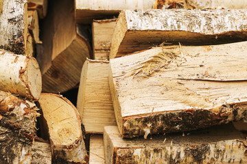 Cut firewood stacked in pile. Closeup of chopped birch logs prepared for burning. Rustic natural background with textured wooden pieces. Autumn energy source. Eco heating material for fireplace stove.