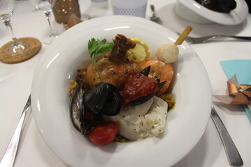 Assiette creuse de paella servie lors d’un mariage – plat méditerranéen avec couverts élégants sur table de réception