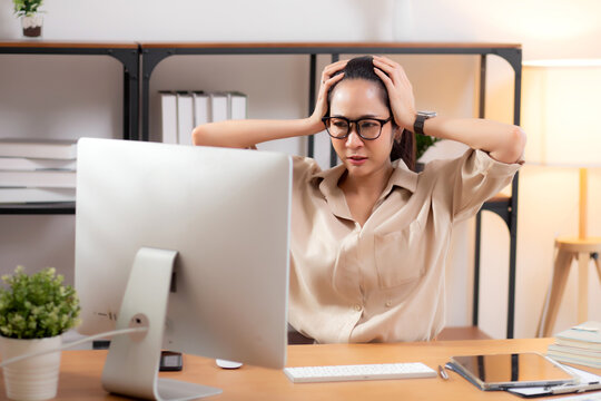 Unhappy young asian businesswoman using desktop computer with frustrated and stress, business woman working with anxiety and exhausted, depression and burnout, business problem and worried.