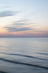 A dreamy, impressionistic paint like blurred sea sunset background with gently soft pastel colours. Vertical photo.