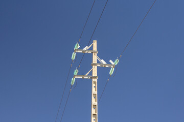 Obraz premium Power lines crossing a clear blue sky on wooden utility pole