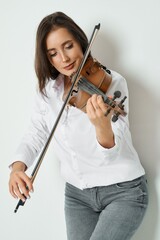 A beautiful woman plays the violin with passion and skill in a simple studio setting.
