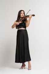 A beautiful woman plays a violin, showcasing musical talent and a classic performance.