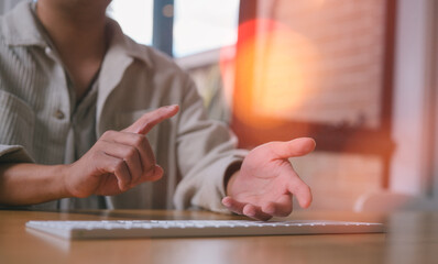 Close-up of hands gesturing while using a computer keyboard, representing discussion, online meeting, teamwork, planning, brainstorming, communication, and remote work in modern digital business.