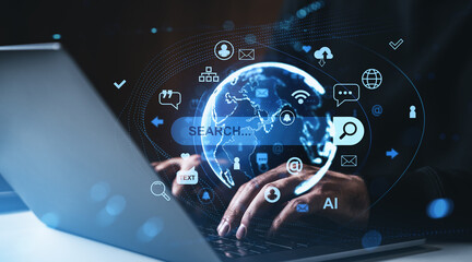 Digital search technology concept with holographic globe and internet icons over hands typing on laptop in dark futuristic environment..