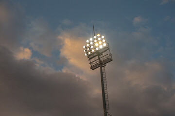 Football Stadium Floodlights at Sunset with Clouds – Concept of Soccer and Sport Atmosphere