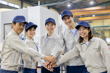 工場の中で円陣を組む作業員グループ